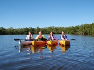 Four people posing for a photo on a kayak