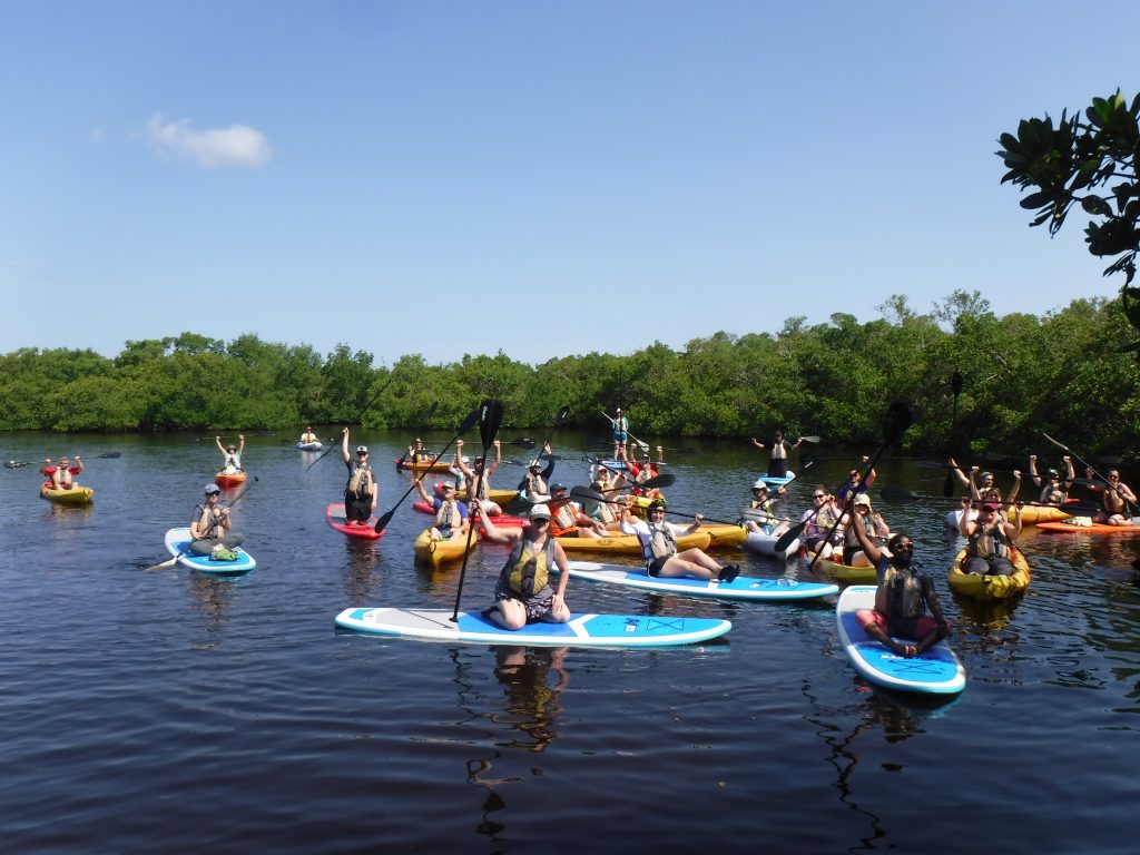 People on SUP and kayaks raising their paddles
