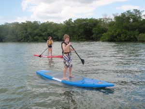 A boy and a girl riding stand up paddleboard
